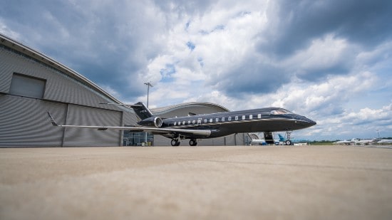 A black private jet in front of a hangar.