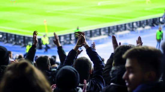 Football fans supporting a game from the stadium stands.